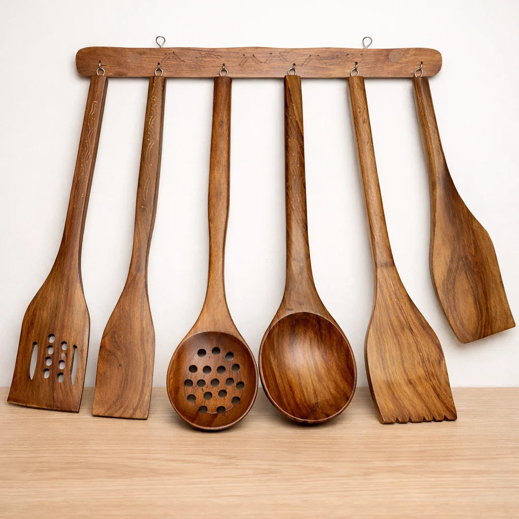Set of wooden kitchen utensils hanging on a wooden rack against a white background